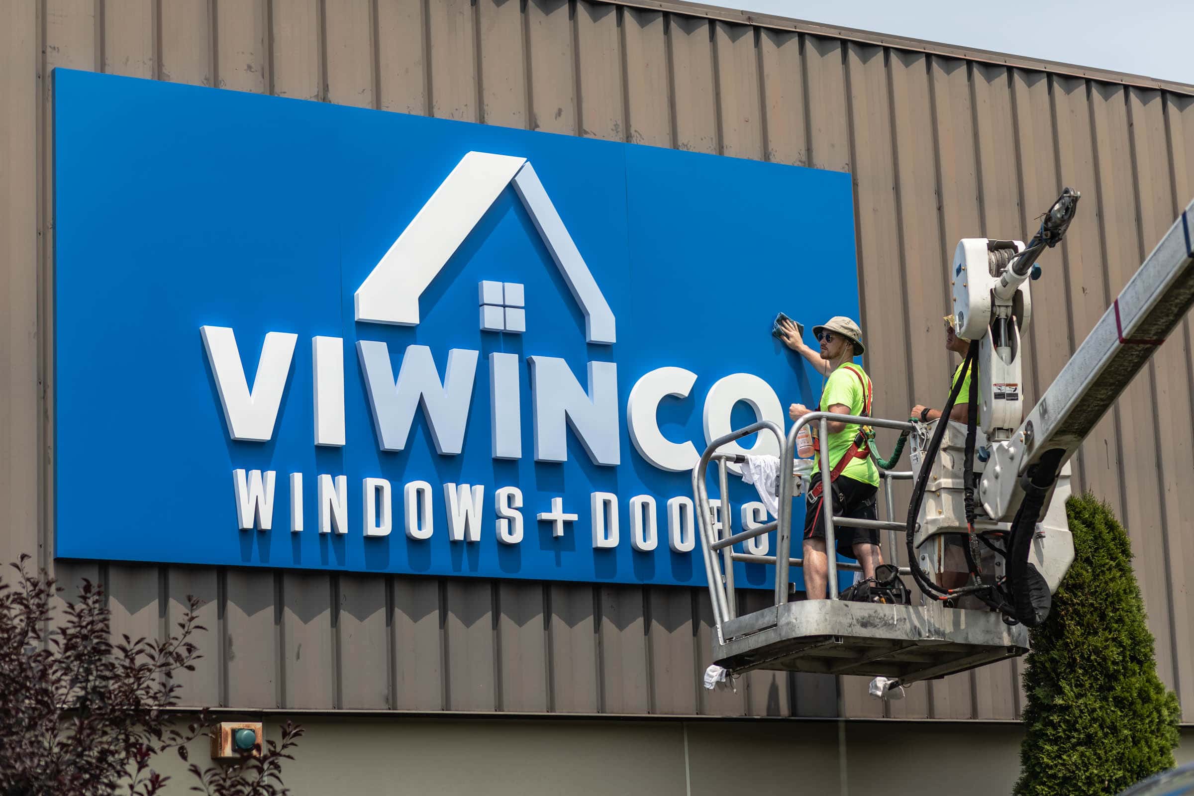 Construction worker buffing Viwinco sign with new branding.