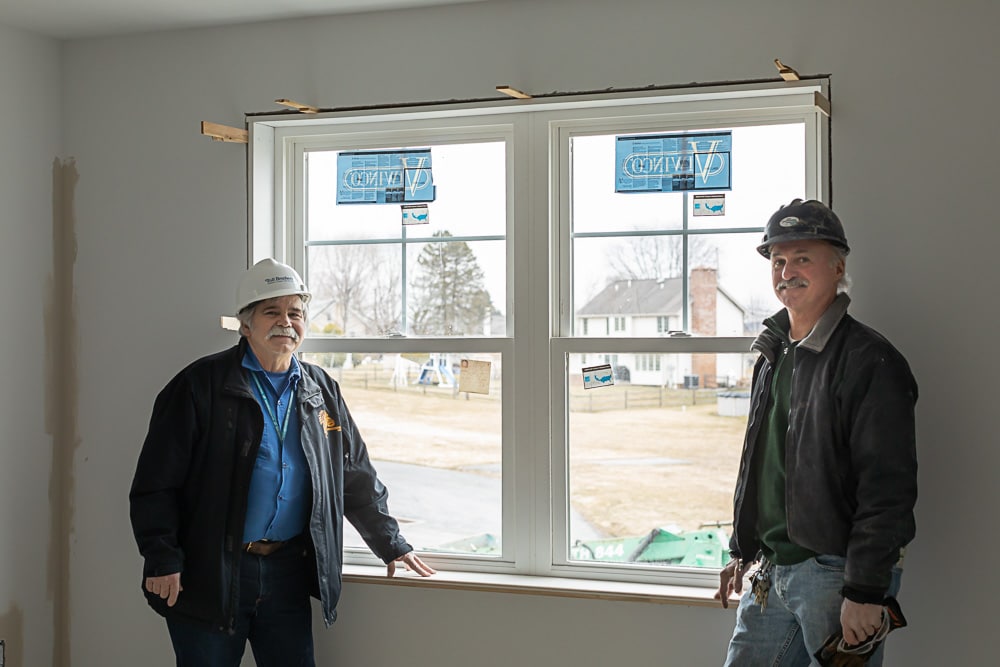 Two older men posing with newly installed Viwinco window