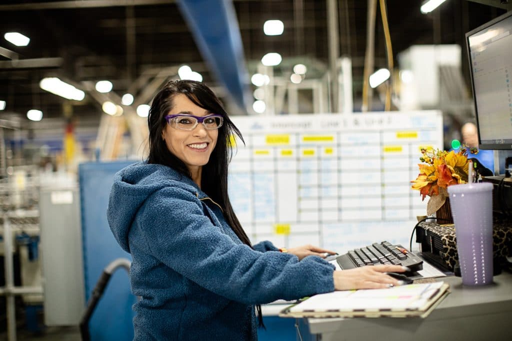 Portrait of smiling woman wearing safety goggles in warehouse