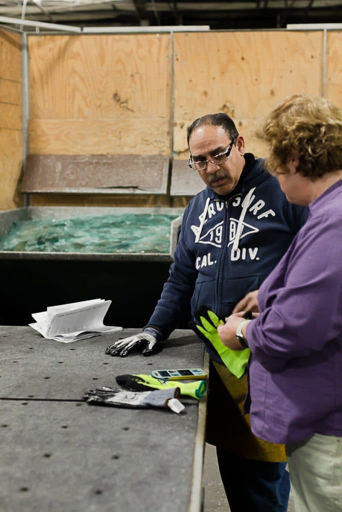 Man speaking to woman in glass production warehouse
